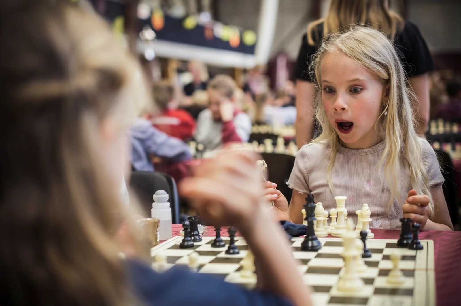 Child discovering through chess A child reacting with excitement during a chess-based learning activity.